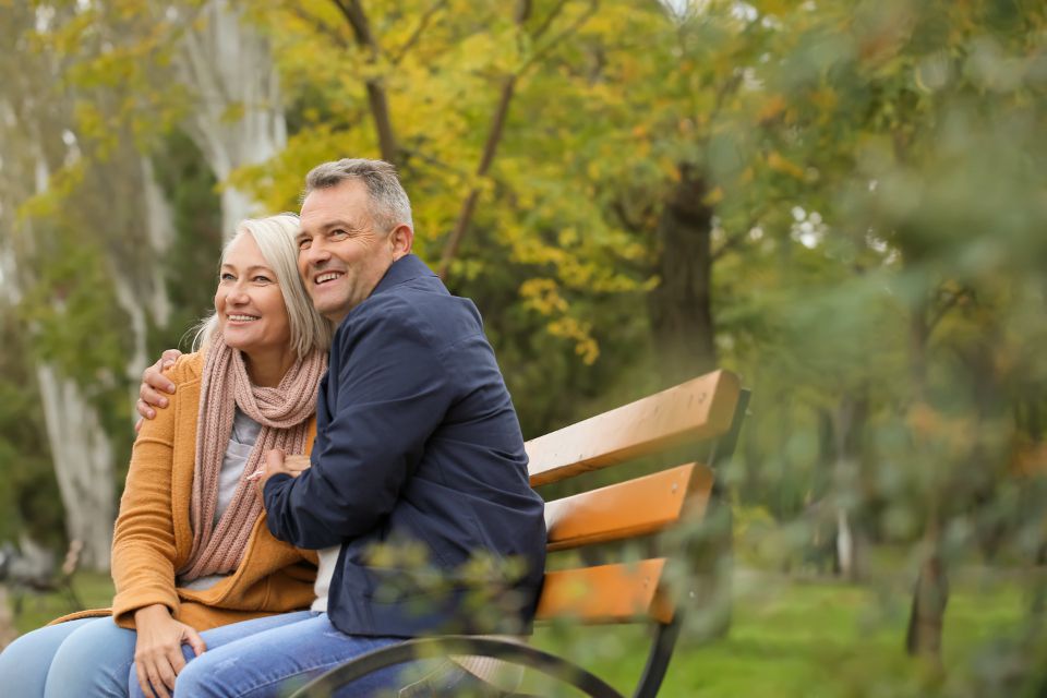 Senior couple sitting together on a park bench in autumn